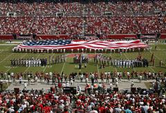 Delayed Enlistment Program members holding giant American flag on stadium field
