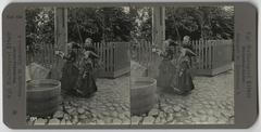 Girls in traditional Danish national costumes standing by a water pump in 1904