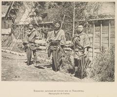 Three men with umbrellas and luggage traveling on the Nakasendo road in Japan in the 1880s