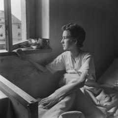 Emaciated woman lying in bed looking out through a window in Bergen-Belsen concentration camp in 1945