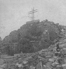 Cross above a makeshift altar at Pawiak prison ruins with window bars visible in the center in Warsaw