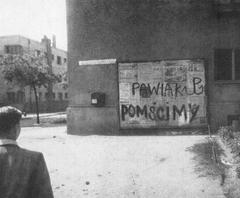 Graffiti text 'Pawiak pomścimy' on a building at Słowacki Street in Warsaw
