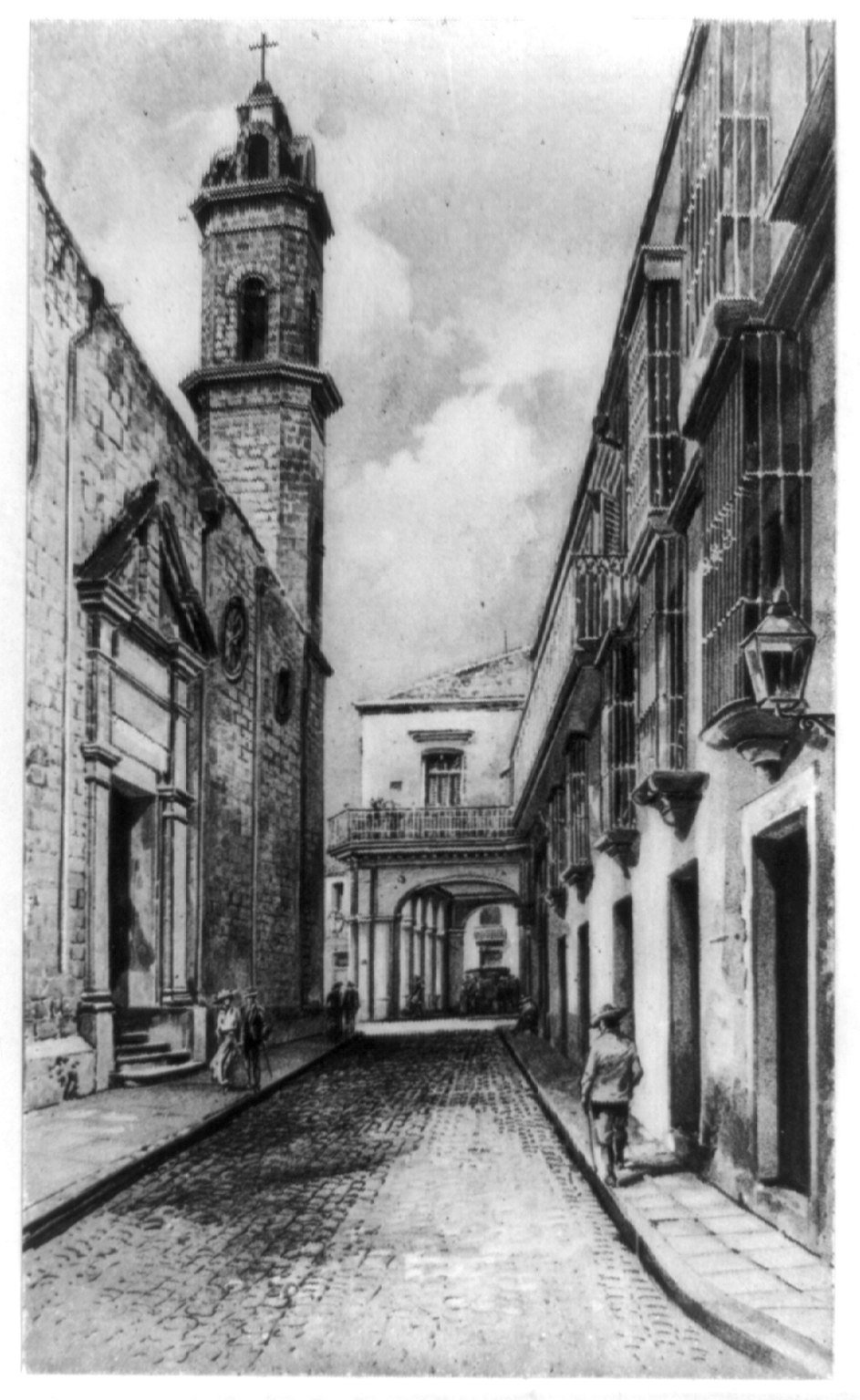 Narrow cobblestone street in old Havana with colorful colonial buildings and a church on the left