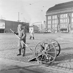 Worker sweeping Mannerheimintie street in front of the Postitalo building in Helsinki, 1955