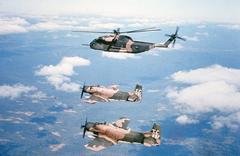 Two U.S. Air Force Douglas A-1H Skyraider aircraft escorting a Sikorsky HH-53C Super Jolly Green Giant rescue helicopter in flight in 1971
