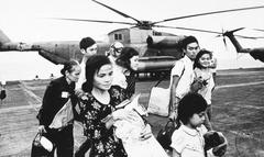 Evacuees from Vietnam on flight deck of USS Midway aircraft carrier during Operation Frequent Wind in 1975 with HH-53 Super Jolly Green Giant helicopter in background