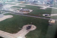 Aerial view of Hahn Air Base in Germany with a USAF Sikorsky HH-53C Super Jolly Green Giant helicopter in the foreground before runway camouflage