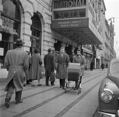Two men walking behind a baby stroller in a busy shopping street in Copenhagen in March 1954