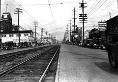 Historic street view of First Avenue South between South Lander Street and South Forest Street in Seattle on February 26, 1927, showing cobblestone streets, street railroad tracks, utility poles, and the Sears Tower on the left