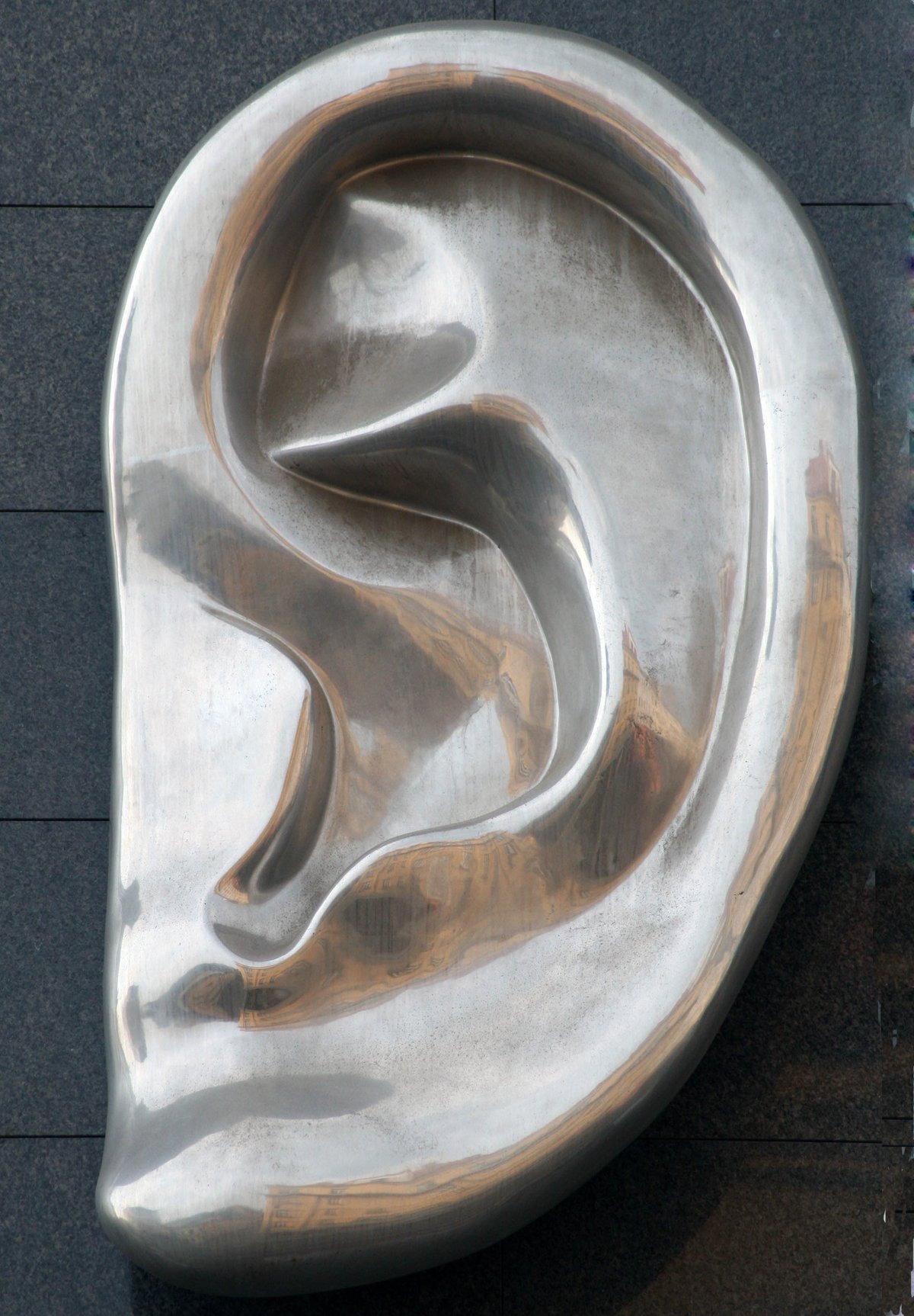 Satinského protruding ear sculpture on the facade of a building on Dunajská Street in Bratislava