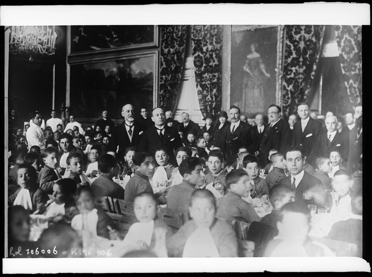 Benito Mussolini hosting a banquet for orphans at the Throne Room of Palazzo Chigi in Rome, with Governor Filippo Cremonesi to his right, December 1925
