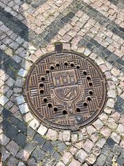 Decorative manhole cover with intricate geometric pattern in Staré Zámecké Schody, Hradčany, Prague, Czech Republic