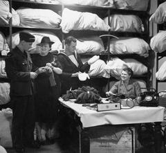 South African Volunteer Service members trying on gloves and mittens in South Africa House stockroom London 1941