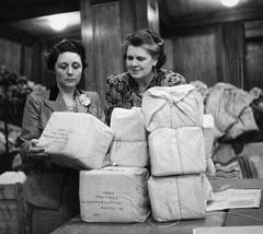 Two women, Mrs Waterson and Mrs Thompson, checking parcels in the Packing Room at South Africa House, London, 1941