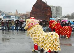 Lion dancers performing on Hyde Street Pier during Chinese New Year celebration with brown sail of Chinese junk ship in background