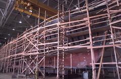 Wooden hull of the lumber schooner C.A. Thayer covered with scaffolding during rehabilitation inside a decommissioned seaplane hangar