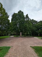 Andreas Hofer Park in Mantua with lush green trees and paved pathways under a clear blue sky