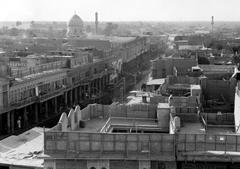 Historical black and white photograph of a street scene in Baghdad with people walking and traditional buildings