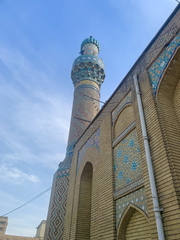 Old stone minaret of the Haydar-Khana Mosque in Baghdad against a blue sky