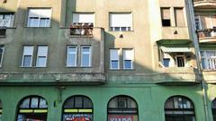 Street view of Népszínház utca with buildings and parked cars