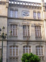 Facade of the Escuela Municipal de Artes y Oficios in Vigo under a partly cloudy sky