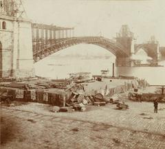 Construction of roadbed above completed arches on Eads Bridge with staging area for equipment in foreground