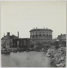 Black and white platinum print photograph of the burnt docks of La Villette, showing the pavilion with offices after fire damage, 19th arrondissement, Paris, 1871