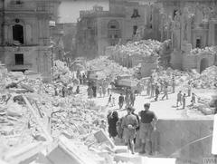 Bomb-damaged Kingsway street in Valletta Malta with service personnel and civilians clearing debris
