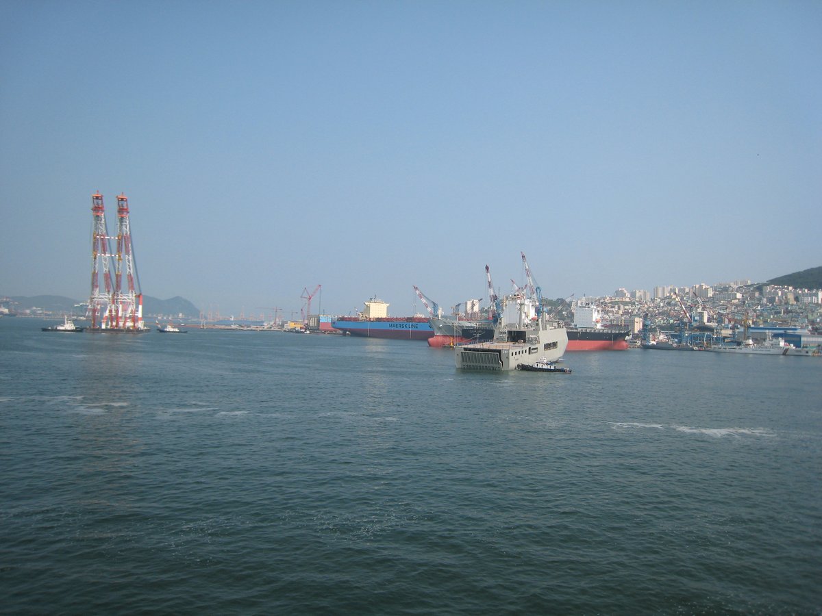 Busan ferry terminal with multiple docks and ferries under a clear sky