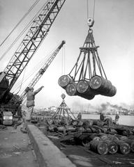 U.N. fuel dump at Inchon Harbor with hundreds of fuel drums being lifted and moved with cranes from a tanker on March 7, 1952