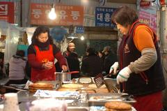 Ajummas frying bindaetteok (Korean mung bean pancakes) at Gwangjang Market in Seoul