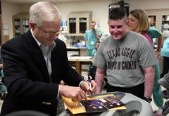 Defense Secretary Robert M. Gates signing a graduation photo at Brooke Army Medical Center