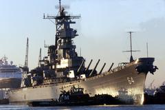 Tug boat pushes the bow of battleship USS Wisconsin at Norfolk Naval Shipyard