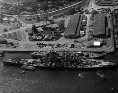 USS Wisconsin (BB-64) battleship tied alongside the hulk of USS Oklahoma (BB-37) at Pearl Harbor Navy Yard with anti-torpedo netting visible