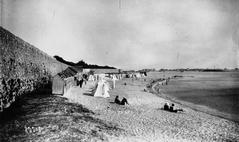 Vintage photograph of Port-Louis beach in 1920 with people enjoying the shore and calm sea