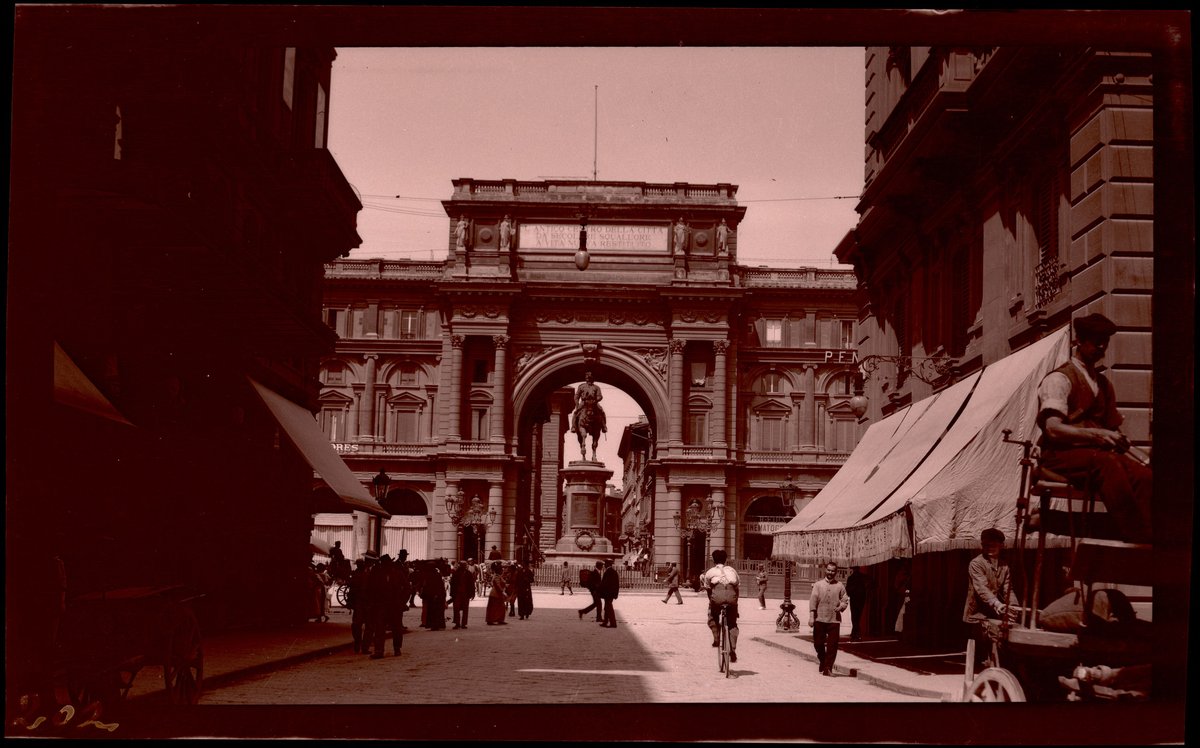 Pedestrians walking beneath the arch at Piazza della Repubblica in Florence with the equestrian statue of Victor Emmanuel II in front