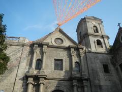 Street view of Intramuros in Manila showing historic landmarks including San Agustin Church, Manila Cathedral facade with Clock Tower-Belfry and Dome, Plaza de Roma with 1886 Fountain and King Charles IV monument