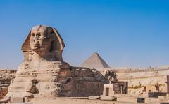 Ancient Egyptian Sphinx with the third pyramid of Giza in the background