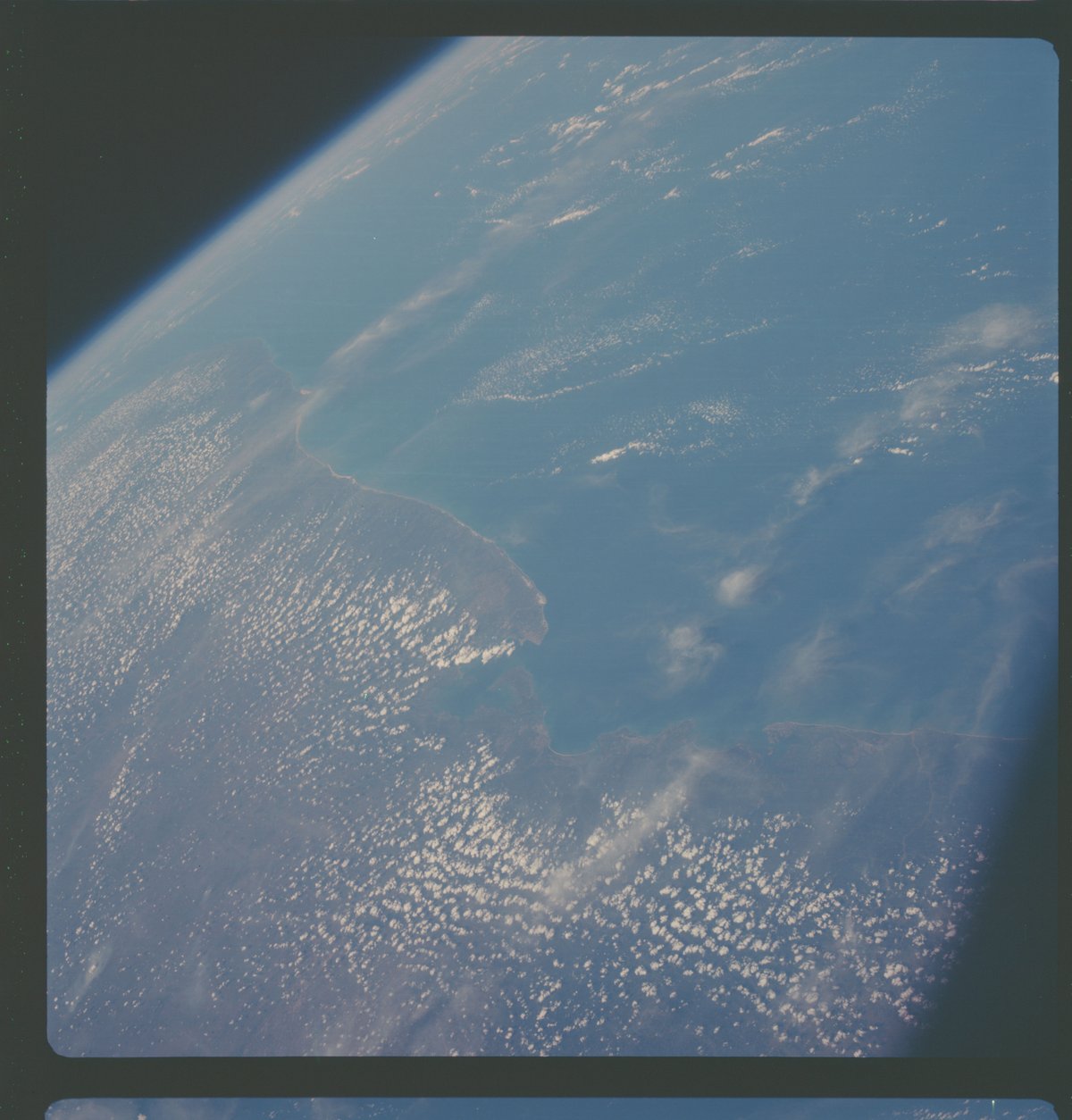 High oblique view of Salvador, Bahia State, Brazil from Apollo 7 showing Earth limb and partial cloud cover