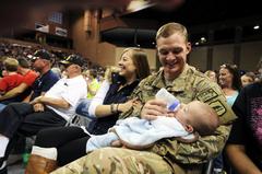 U.S. Army soldier holding his son for the first time with his wife at homecoming event