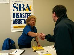 Josephine Rubio, SBA representative, shaking hands with federal coordinating officer Justin Dombrowski at Mitchell Disaster Recovery Center