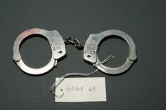 Pair of handcuffs connected by steel chain with markings on one cuff