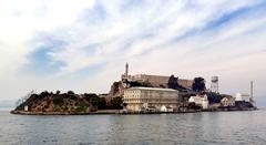 Aerial view of Alcatraz Island in San Francisco Bay with historic buildings and surrounding water under clear sky