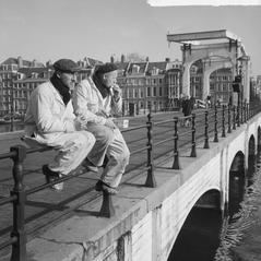 Two workers enjoying the sun on Magere Brug on the first summer day in February 1965 in Amsterdam