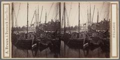 Historic view of the Amstel River with Magere Brug bridge and boats in the foreground, nursing home De Amstelhof visible in the background