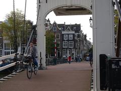 Woman biking over the wooden Skinny Bridge (Magere Brug) across the Amstel river in Amsterdam