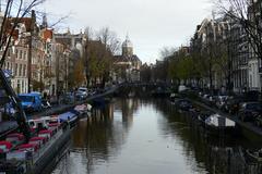 Oudezijds Voorburgwal canal lined with historic buildings and boats in Amsterdam with Sint Niklaaskerk church in the background
