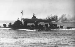 USS Intrepid aircraft carrier afire after kamikaze hit near Okinawa, Fletcher-class destroyer passing by