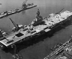 USS Intrepid aircraft carrier undergoing SCB-27C modernization at Newport News Shipbuilding with new island, steam catapults, and aft deck edge elevator installed