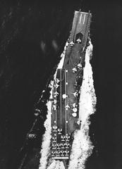 Aerial view of USS Intrepid aircraft carrier underway with various military planes on deck in 1959